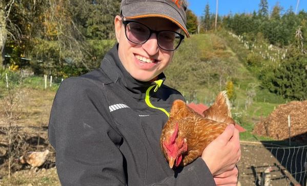 Das Bild zeigt eine jungen Frau mit einem Huhn auf dem Arm