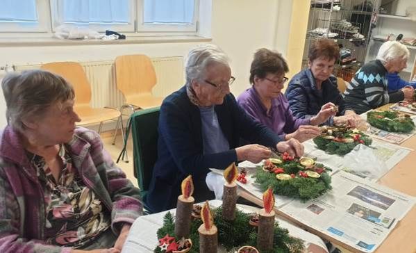 Das Bild zeigt Bewohnerinnen beim Verzieren von Adventskränzen