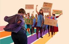 Theater Eine Person im Vordergrund hat die Arme ausgestreckt und eine Personengruppe hebt Schilder in die Höhe.
