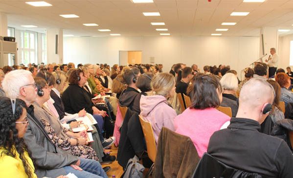 Fachtag Sehr viele Personen sitzen im Publikum bei einem Vortrag.