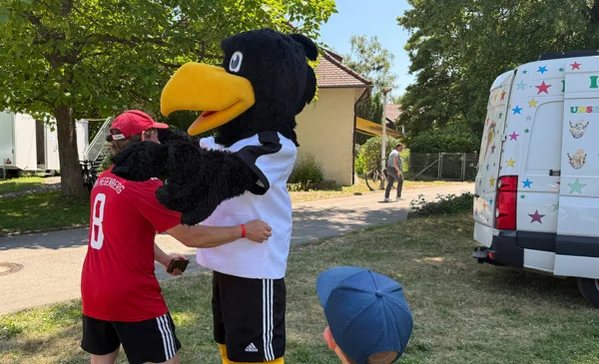 Pokal Das Maskottchen begrüßt einen Bewohner.