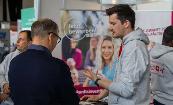 Karriere Kick 2026 Zwei Männer unterhalten sich an einem Messestand