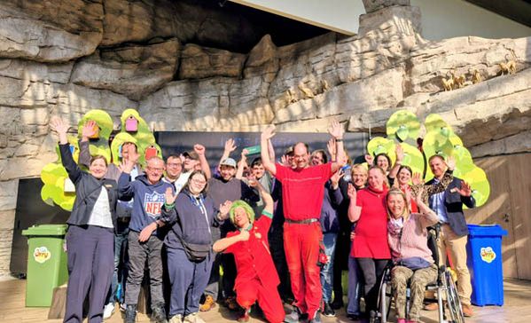 Spende Viele Personen bei einem Gruppenbild strecken die Hände in die Luft.