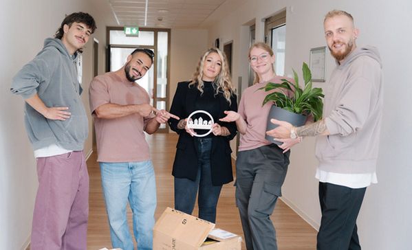 Wohnraum Mehrere Personen stehen in einem Gebäude mit Umzugsgegenständen wie einem Karton und einer Pflanze.