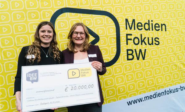 Förderpreis Zwei Frauen halten einen Scheck und lächeln in die Kamera.