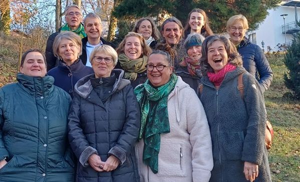 Gruppenbild Das Bild zeigt eine Gruppe von Personen, die alle in einem Wald stehen und in die Kamera lächeln.