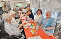 Sommerfest Mehrere Personen sitzen an einem Tisch in einem Festzelt.
