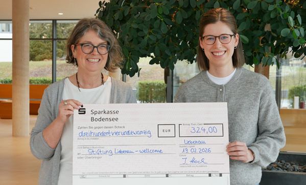 Spendenübergabe Zwei Frauen halten einen Scheck bei einer Spendenübergabe im Foyer.