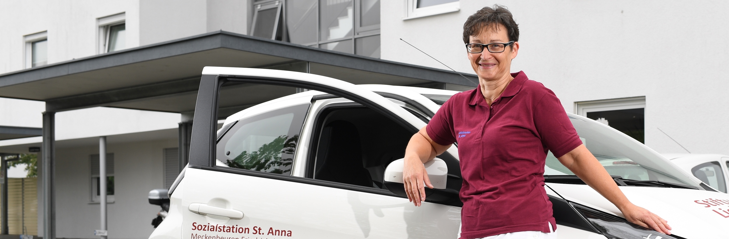 Das Bild zeigt eine Frau vor einem offenen Auto