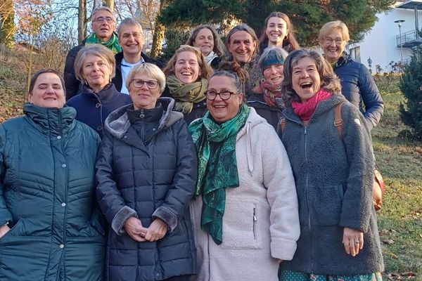 Gruppenbild Das Bild zeigt eine Gruppe von Personen, die alle in einem Wald stehen und in die Kamera lächeln.