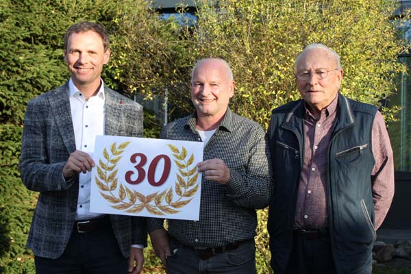 Ehrung Gruppenbild von drei Männern mit einem Schild "30".