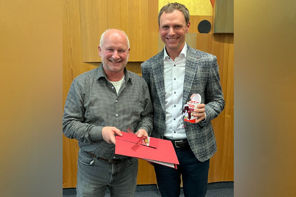 Ehrung Ein Mann übergibt einem anderen Mann eine Urkunde und ein Geschenk.