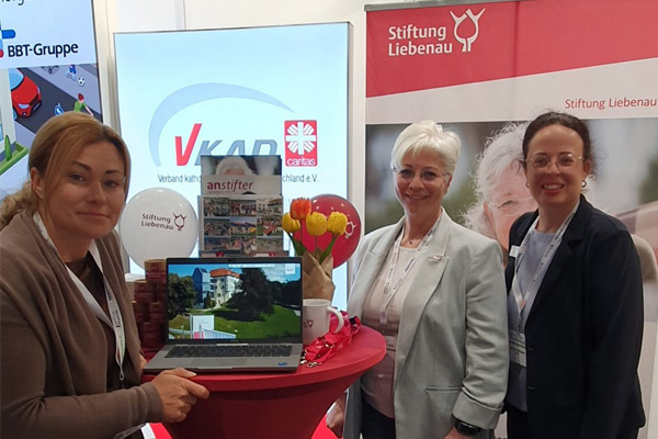 Pflegetag in Berlin Drei Frauen stehen an einem Messestand und lächeln in die Kamera.