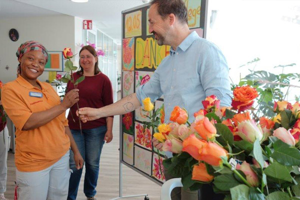 Tag der Pflege Das Foto zeigt wie der Einrichtungsleiter eine Rose überreicht.