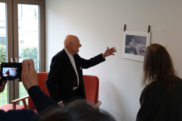 Persönliche Führung des Künstlers Ein älterer Mann erklärt ein Foto